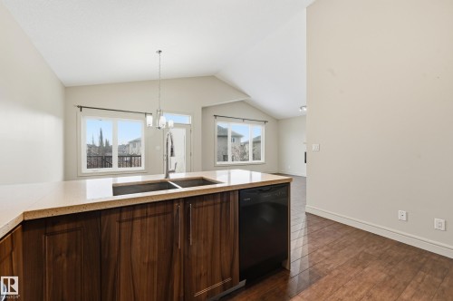 Kitchen with dishwasher, a chandelier, lofted ceiling, dark wood-type flooring, and dark wood finish cabinets - 1346 Cunningham Drive W, Edmonton, AB - Indoor Photo Showing Kitchen With Double Sink