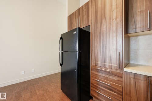 Kitchen featuring wood finish cabinetry, freestanding refrigerator, light stone counters, and dark wood-style floors - 1346 Cunningham Drive W, Edmonton, AB - Indoor