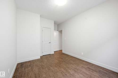 Unfurnished bedroom with dark wood-style floors and a textured ceiling - 1346 Cunningham Drive W, Edmonton, AB - Indoor Photo Showing Other Room