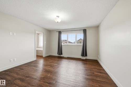 Empty room with dark wood-type flooring and a textured ceiling - 1346 Cunningham Drive W, Edmonton, AB - Indoor Photo Showing Other Room