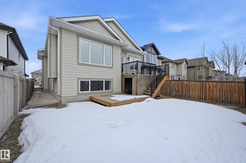 Snow covered house with a fenced backyard, a deck, and a residential view - 1346 Cunningham Drive W, Edmonton, AB - Outdoor With Exterior