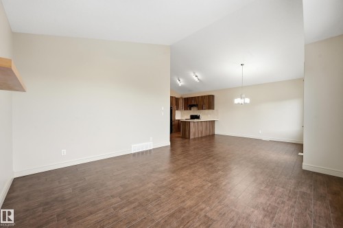 Unfurnished living room featuring lofted ceiling, dark wood-style flooring, and suspended lighting - 1346 Cunningham Drive W, Edmonton, AB - Indoor