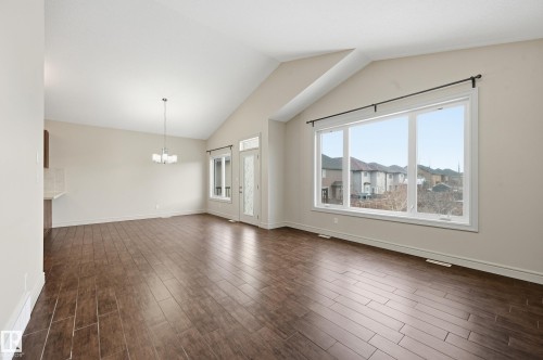 Unfurnished living room with dark wood-style floors and hanging lights - 1346 Cunningham Drive W, Edmonton, AB - Indoor