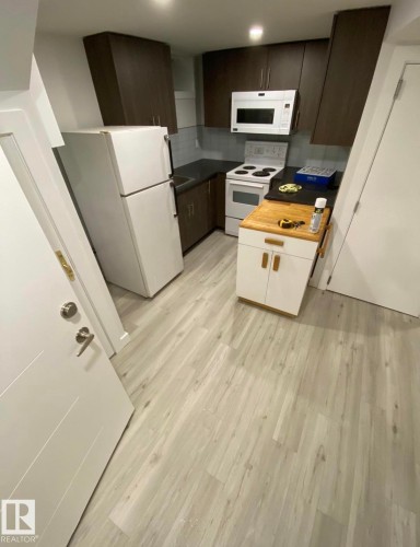 Kitchen with white appliances, light wood finished floors, and two tone color scheme - 13524 62 Street, Edmonton, AB - Indoor Photo Showing Kitchen