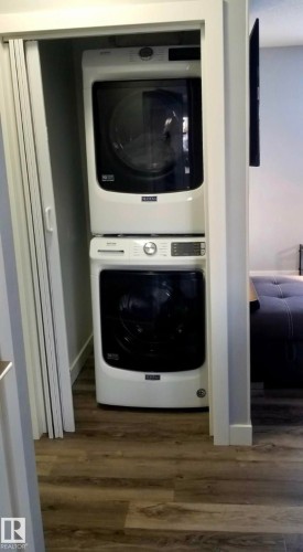 Laundry room featuring stacked washing machine and dryer and dark wood-type flooring - 13524 62 Street, Edmonton, AB - Indoor Photo Showing Laundry Room