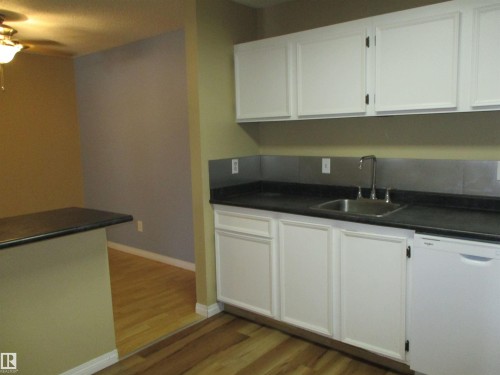 Kitchen with dishwasher, white cabinetry, dark countertops, a ceiling fan, and light wood-type flooring - 1186 Saddleback Road, Edmonton, AB - Indoor Photo Showing Kitchen