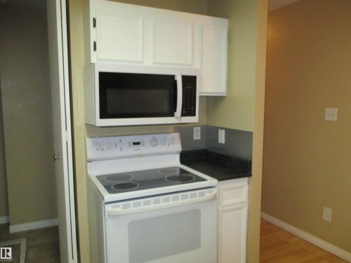 Kitchen with white appliances, white cabinets, dark countertops, and light wood-type flooring - 1186 Saddleback Road, Edmonton, AB - Indoor Photo Showing Kitchen