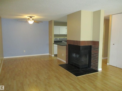 Unfurnished living room featuring a brick fireplace, light wood finished floors, ceiling fan, and a textured ceiling - 1186 Saddleback Road, Edmonton, AB - Indoor Photo Showing Living Room With Fireplace