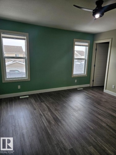 Spare room featuring dark wood-style floors, a textured ceiling, and ceiling fan - 208 Kirpatrick Way, Leduc, AB - Indoor Photo Showing Other Room