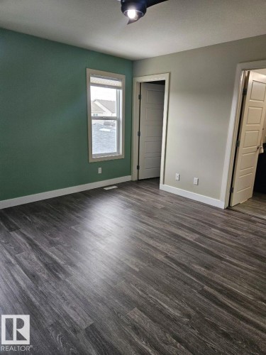 Unfurnished bedroom with dark wood-type flooring and a closet - 208 Kirpatrick Way, Leduc, AB - Indoor Photo Showing Other Room