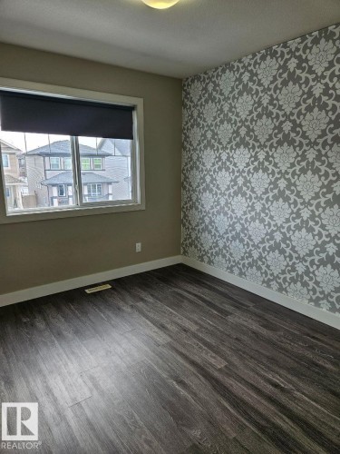 Spare room with wallpapered walls, dark wood-style floors, and a textured ceiling - 208 Kirpatrick Way, Leduc, AB - Indoor Photo Showing Other Room
