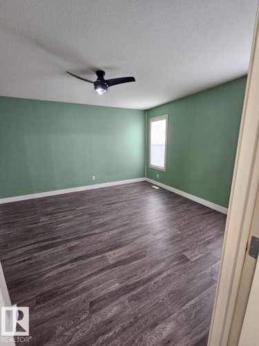 Spare room with dark wood-type flooring, ceiling fan, and a textured ceiling - 208 Kirpatrick Way, Leduc, AB - Indoor Photo Showing Other Room