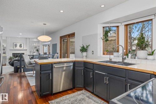 Kitchen featuring dishwasher, decorative light fixtures, dark wood-style flooring, open floor plan, and a fireplace - 175 Roy Street, Edmonton, AB - Indoor Photo Showing Other Room