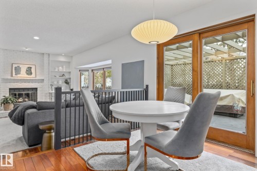 Dining area featuring wood-type flooring, a brick fireplace, a textured ceiling, and built in shelves - 175 Roy Street, Edmonton, AB - Indoor Photo Showing Dining Room With Fireplace