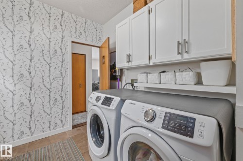 Laundry room featuring wallpapered walls, a textured ceiling, washing machine and dryer, and cabinet space - 175 Roy Street, Edmonton, AB - Indoor Photo Showing Laundry Room