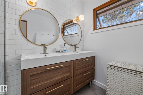 Bathroom featuring double vanity, dark tile patterned floors, decorative backsplash, and tile walls - 175 Roy Street, Edmonton, AB - Indoor Photo Showing Bathroom