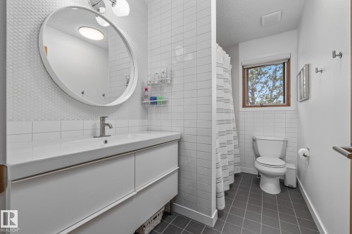 Full bath featuring vanity, dark tile patterned floors, tile walls, curtained shower, and a textured ceiling - 175 Roy Street, Edmonton, AB - Indoor Photo Showing Bathroom