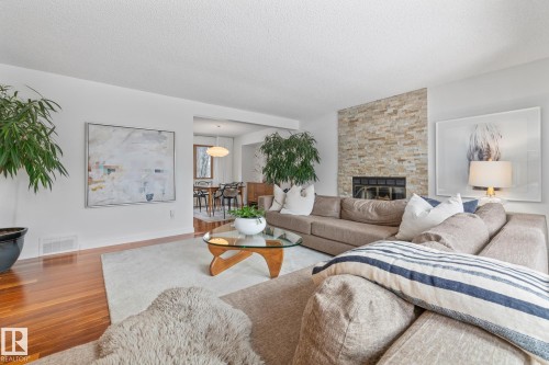 Living room featuring a stone fireplace, wood finished floors, and a textured ceiling - 175 Roy Street, Edmonton, AB - Indoor Photo Showing Living Room With Fireplace