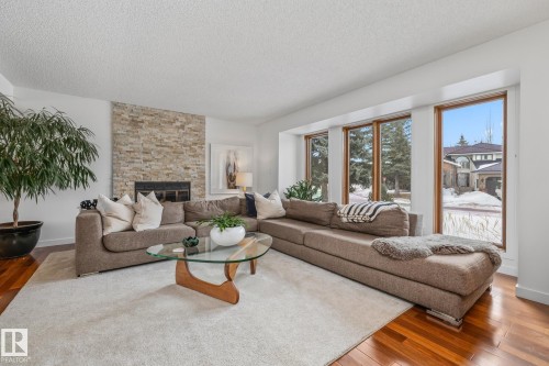 Living room with wood-type flooring, a textured ceiling, and a stone fireplace - 175 Roy Street, Edmonton, AB - Indoor Photo Showing Living Room With Fireplace