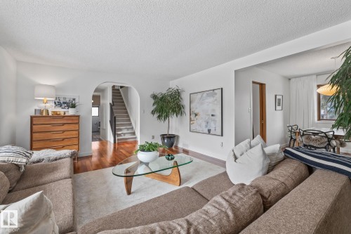 Living area featuring wood finished floors, arched walkways, and a textured ceiling - 175 Roy Street, Edmonton, AB - Indoor Photo Showing Living Room