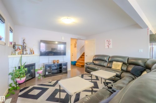 Living room featuring a tiled fireplace and wood finished floors - 5244 1A Avenue Sw, Edmonton, AB - Indoor Photo Showing Living Room With Fireplace