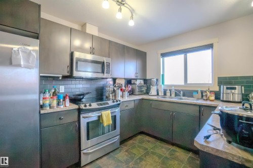 Kitchen featuring stainless steel appliances, tasteful backsplash, and light countertops - 5244 1A Avenue Sw, Edmonton, AB - Indoor Photo Showing Kitchen With Double Sink