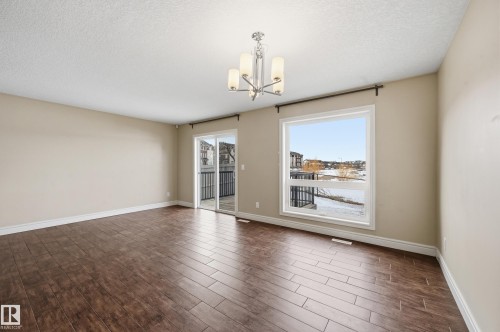Empty room featuring wood tiled floors, a textured ceiling, and hanging lights - 1349 Cunningham Drive, Edmonton, AB - Indoor