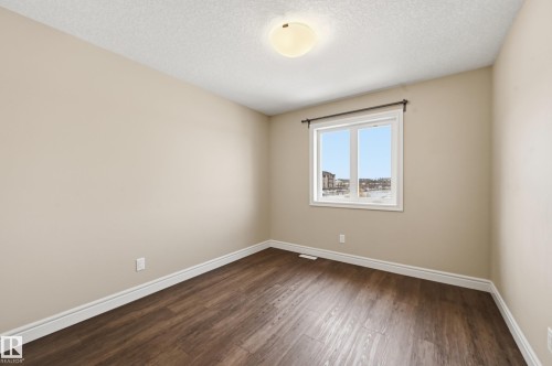 Unfurnished room featuring dark wood-type flooring and a textured ceiling - 1349 Cunningham Drive, Edmonton, AB - Indoor Photo Showing Other Room