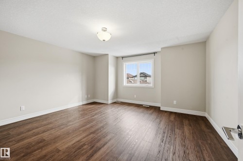 Empty room with dark wood-style floors and a textured ceiling - 1349 Cunningham Drive, Edmonton, AB - Indoor Photo Showing Other Room