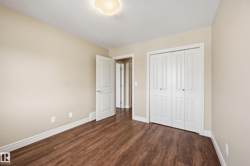 Unfurnished bedroom with a textured ceiling, dark wood-type flooring, and a closet - 1351 Cunningham Drive, Edmonton, AB - Indoor Photo Showing Other Room