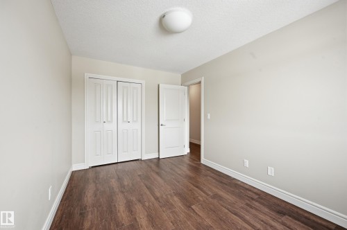 Unfurnished bedroom featuring dark wood finished floors, a textured ceiling, and a closet - 1351 Cunningham Drive, Edmonton, AB - Indoor Photo Showing Other Room