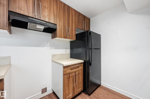 Kitchen with wood finish cabinetry, freestanding refrigerator, and light wood-type flooring - 1351 Cunningham Drive, Edmonton, AB - Indoor Photo Showing Kitchen
