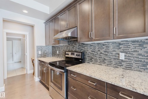 Kitchen featuring electric stove, light stone countertops, backsplash, recessed lighting, and light wood finished floors - 1957 Ainslie Link, Edmonton, AB - Indoor Photo Showing Kitchen With Upgraded Kitchen