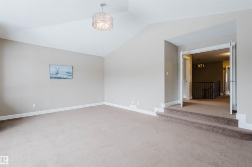 Unfurnished room featuring light colored carpet, lofted ceiling, and suspended lighting - 1957 Ainslie Link, Edmonton, AB - Indoor Photo Showing Other Room