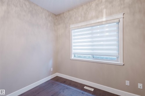 Unfurnished room featuring baseboards and dark wood-style floors - 1957 Ainslie Link, Edmonton, AB - Indoor Photo Showing Other Room