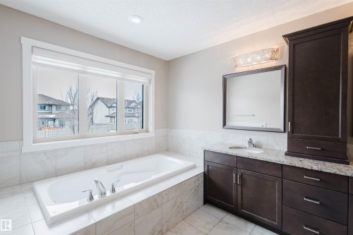 Bathroom with vanity, a bath, and a textured ceiling - 1957 Ainslie Link, Edmonton, AB - Indoor Photo Showing Bathroom