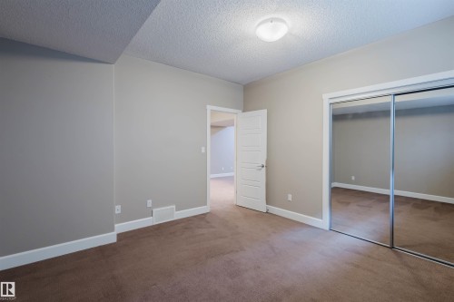 Unfurnished bedroom with carpet flooring, a textured ceiling, and a closet - 1957 Ainslie Link, Edmonton, AB - Indoor Photo Showing Other Room