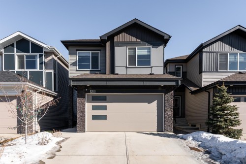 Craftsman-style house featuring stone siding, concrete driveway, a garage, board and batten siding, and a shingled roof - 5211 Kimball Crescent, Edmonton, AB - Outdoor With Facade