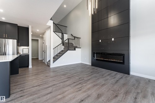 Unfurnished living room with a high ceiling, light wood-type flooring, a fireplace, and recessed lighting - 5211 Kimball Crescent, Edmonton, AB - Indoor With Fireplace