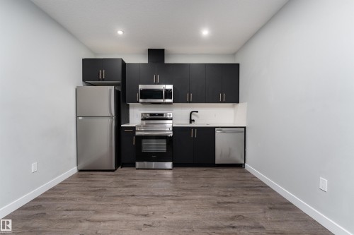 Kitchen featuring stainless steel appliances, dark cabinetry, dark wood-style flooring, decorative backsplash, and recessed lighting - 5211 Kimball Crescent, Edmonton, AB - Indoor Photo Showing Kitchen