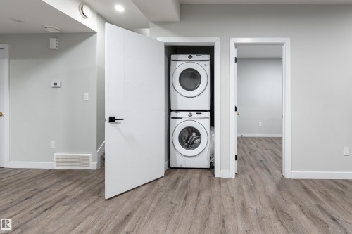 Laundry area featuring stacked washer and dryer and light wood-style flooring - 5211 Kimball Crescent, Edmonton, AB - Indoor Photo Showing Laundry Room