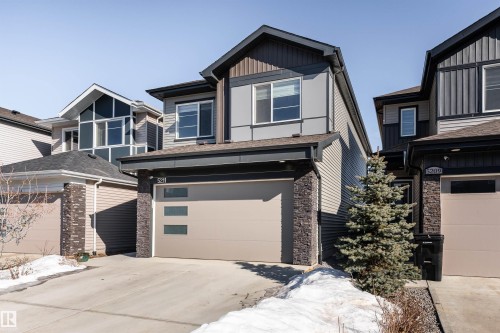 View of front of property featuring stone siding, concrete driveway, a garage, and board and batten siding - 5211 Kimball Crescent, Edmonton, AB - Outdoor