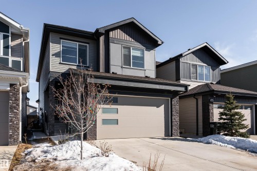 View of front of property with driveway, stone siding, an attached garage, board and batten siding, and a shingled roof - 5211 Kimball Crescent, Edmonton, AB - Outdoor