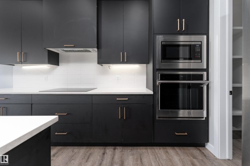 Kitchen with dark cabinets, stainless steel appliances, decorative backsplash, and modern cabinets - 5211 Kimball Crescent, Edmonton, AB - Indoor Photo Showing Kitchen