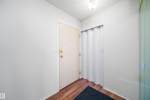 Doorway with a textured ceiling and wood finished floors - 213 5065 31 Avenue, Edmonton, AB - Indoor Photo Showing Other Room