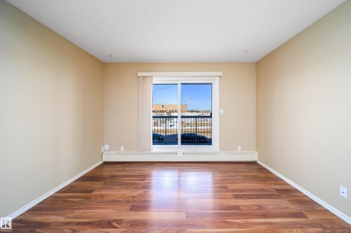Unfurnished room featuring dark wood-style flooring and a baseboard radiator - 213 5065 31 Avenue, Edmonton, AB - Indoor Photo Showing Other Room