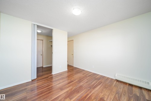 Unfurnished room featuring dark wood-type flooring and a textured ceiling - 213 5065 31 Avenue, Edmonton, AB - Indoor Photo Showing Other Room
