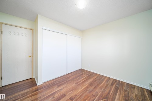 Unfurnished bedroom featuring a closet, dark wood-style floors, and a textured ceiling - 213 5065 31 Avenue, Edmonton, AB - Indoor Photo Showing Other Room
