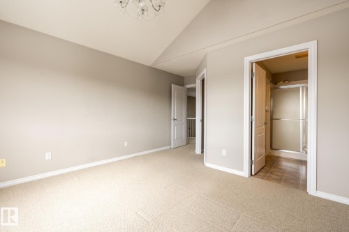 Unfurnished bedroom featuring vaulted ceiling, light colored carpet, hanging lights, and ensuite bathroom - 11622 11 Avenue, Edmonton, AB - Indoor Photo Showing Other Room