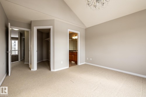 Unfurnished bedroom featuring a spacious closet, suspended lighting, light carpet, lofted ceiling, and ensuite bath - 11622 11 Avenue, Edmonton, AB - Indoor Photo Showing Other Room